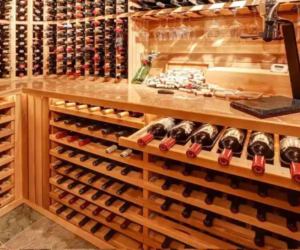 Table de trois restaurants Bordeaux, cave à vins avec casiers en bois chargés de bouteilles, verres suspendus et plan de travail de dégustation éclairé à la lumière chaude