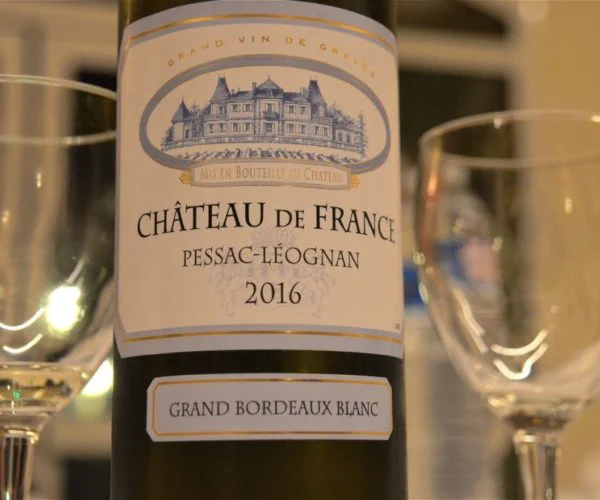Table de trois restaurants Bordeaux, bouteille de Château de France Pessac Léognan 2016, Grand Bordeaux Blanc, au premier plan avec verres à vin en arrière plan